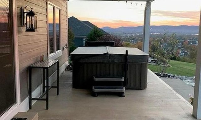 patio terrace at dusk with a mountain view and a hot tub