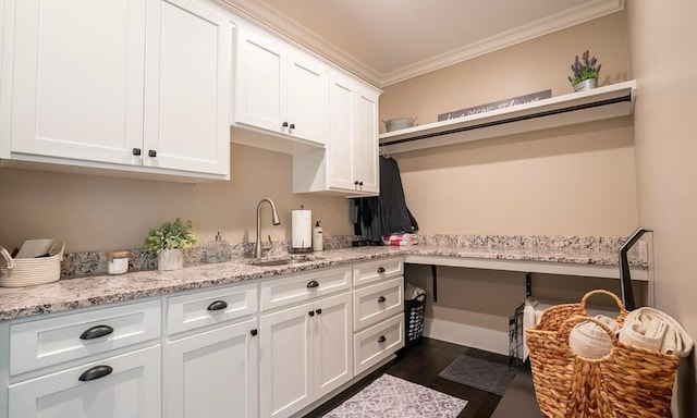 interior space with dark hardwood / wood-style flooring, light stone counters, crown molding, sink, and white cabinets