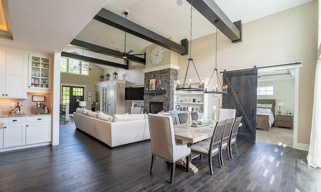 dining area with a barn door, plenty of natural light, high vaulted ceiling, and dark hardwood / wood-style floors