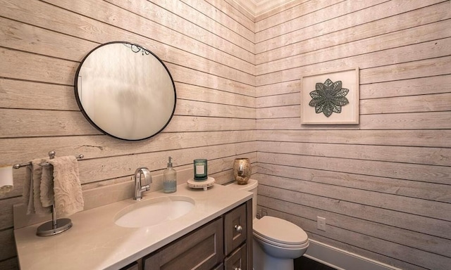 bathroom featuring wooden walls, vanity, and toilet