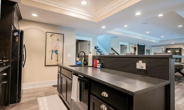 kitchen featuring sink, a raised ceiling, light wood-type flooring, black refrigerator, and ornamental molding