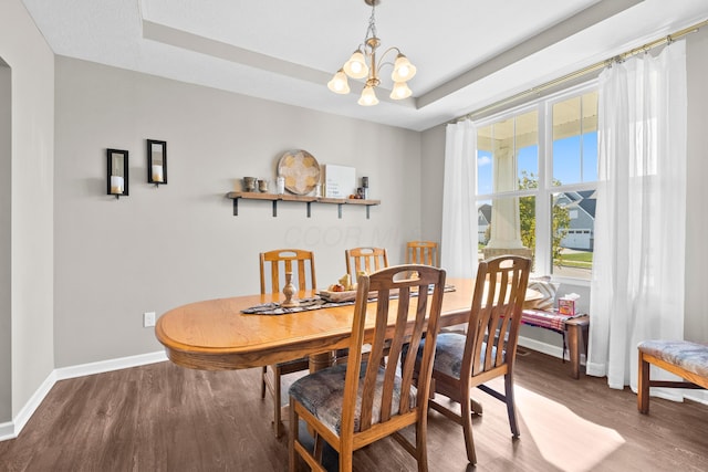 dining area featuring hardwood / wood-style flooring, a notable chandelier, and a raised ceiling