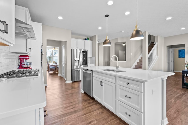 kitchen featuring white cabinets, hanging light fixtures, sink, an island with sink, and appliances with stainless steel finishes