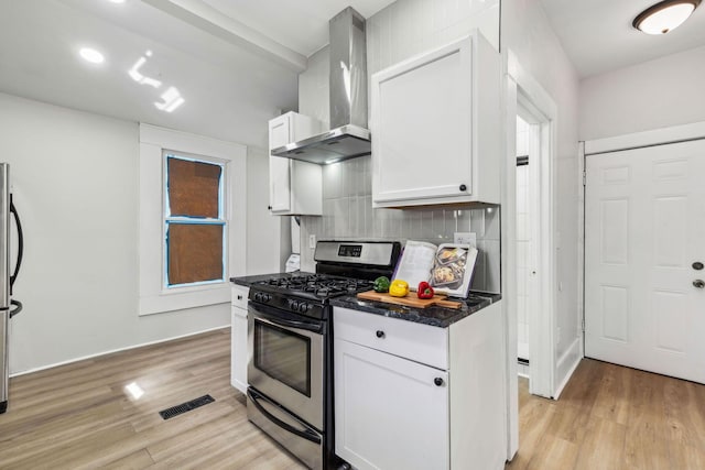 kitchen with white cabinets, light wood-type flooring, wall chimney range hood, and stainless steel appliances