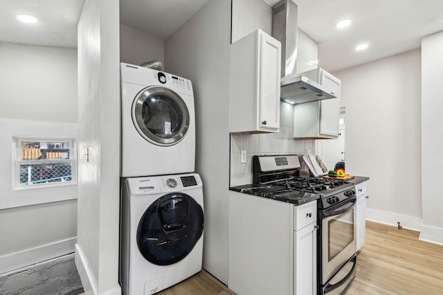 laundry room with stacked washer / drying machine and light wood-type flooring