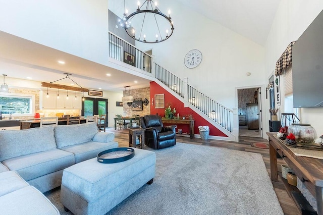 living room with high vaulted ceiling, wood-type flooring, and an inviting chandelier