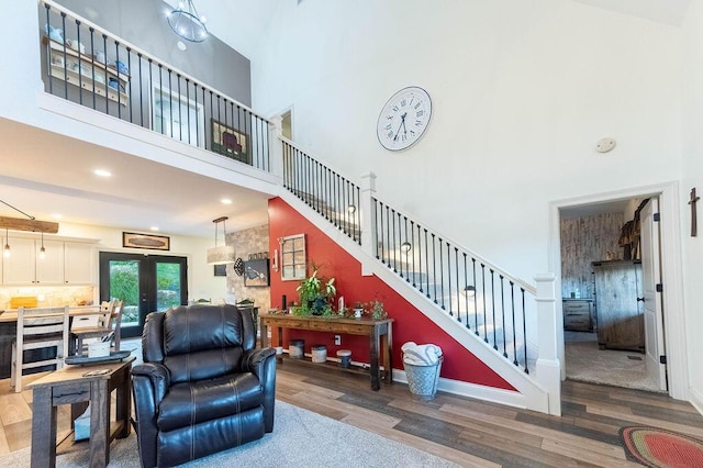 living room with french doors, a towering ceiling, and hardwood / wood-style flooring