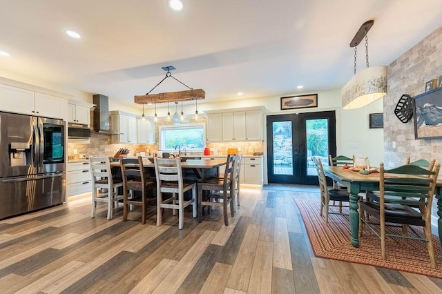 dining space featuring plenty of natural light, light hardwood / wood-style floors, sink, and french doors