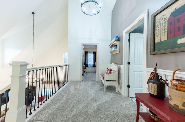 corridor with an inviting chandelier, carpet, and high vaulted ceiling