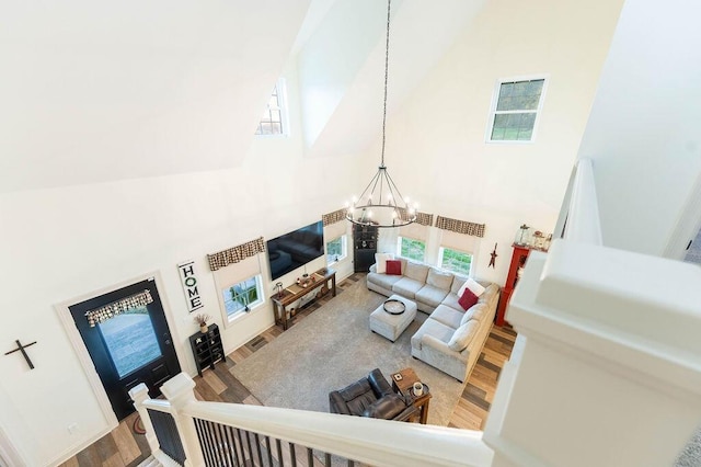 living room featuring high vaulted ceiling, wood-type flooring, and an inviting chandelier