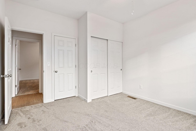 unfurnished bedroom with light carpet and a closet