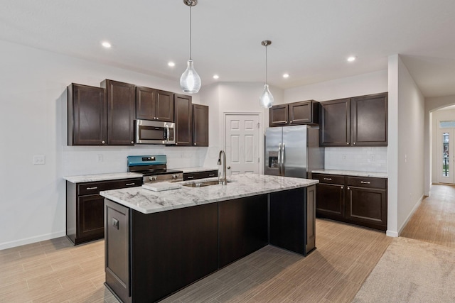 kitchen with pendant lighting, sink, an island with sink, dark brown cabinets, and stainless steel appliances