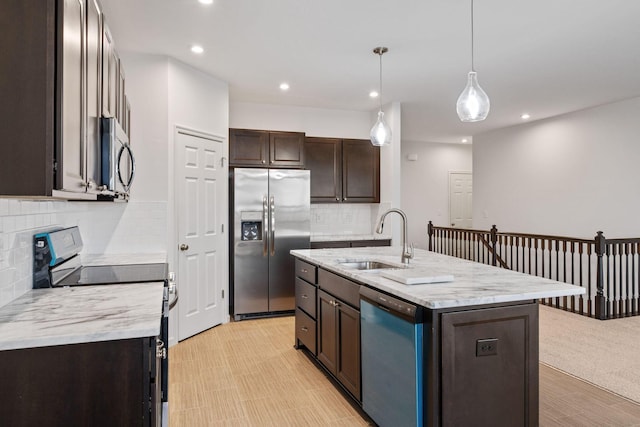 kitchen with sink, stainless steel appliances, an island with sink, decorative light fixtures, and decorative backsplash