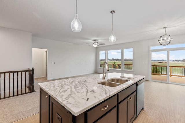 kitchen featuring light stone counters, stainless steel dishwasher, dark brown cabinets, ceiling fan with notable chandelier, and sink