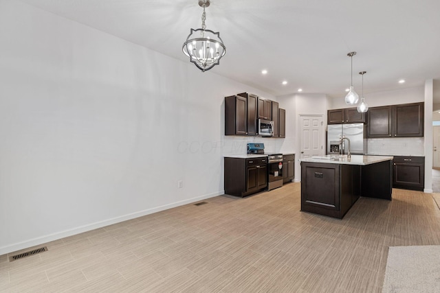 kitchen with a center island with sink, dark brown cabinetry, stainless steel appliances, and hanging light fixtures