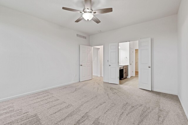 unfurnished bedroom with connected bathroom, ceiling fan, and light carpet