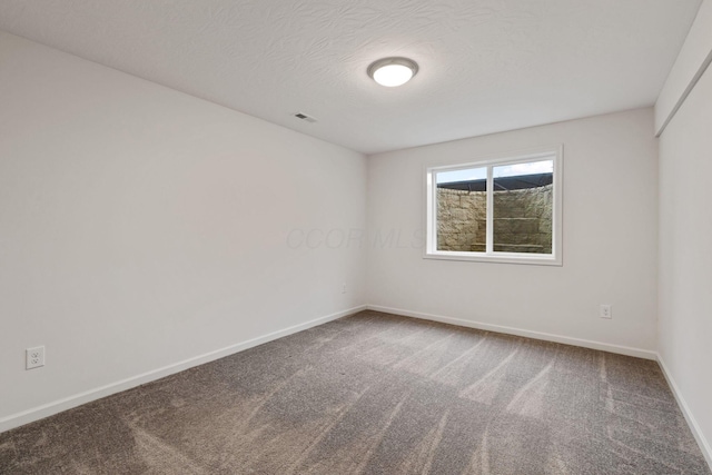 spare room featuring carpet flooring and a textured ceiling