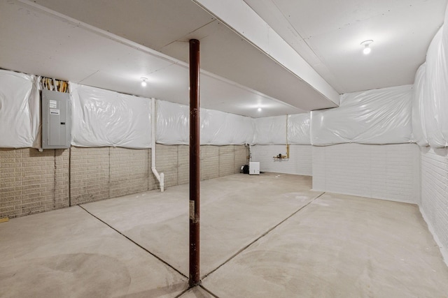 basement featuring electric panel and brick wall