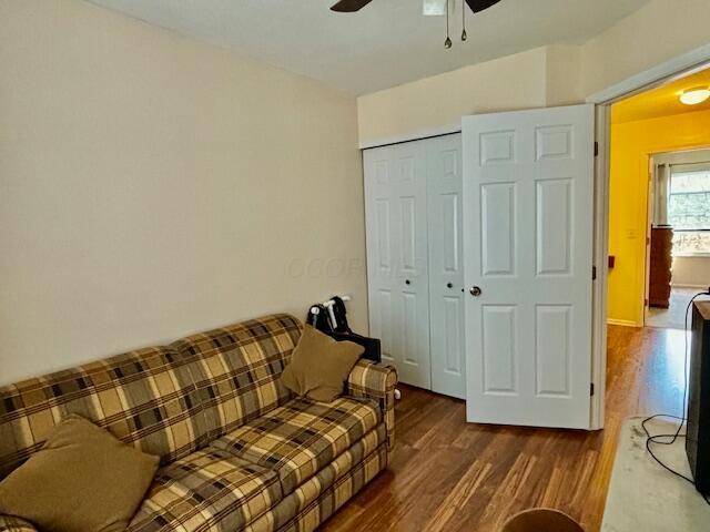 living room featuring ceiling fan and dark hardwood / wood-style flooring