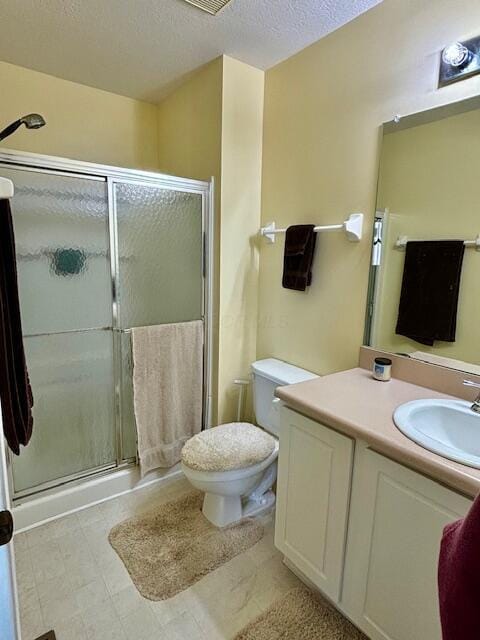 bathroom featuring a textured ceiling, vanity, an enclosed shower, and toilet