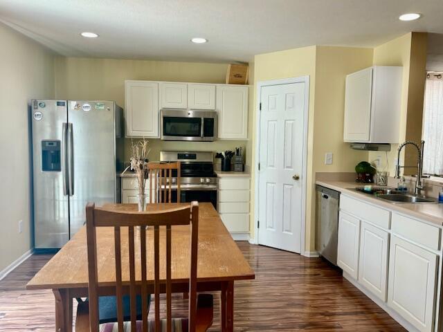 kitchen with stainless steel appliances, white cabinetry, dark hardwood / wood-style floors, and sink