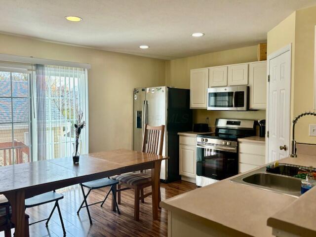 kitchen with dark hardwood / wood-style flooring, sink, white cabinets, and stainless steel appliances