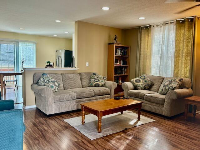 living room featuring ceiling fan and dark wood-type flooring