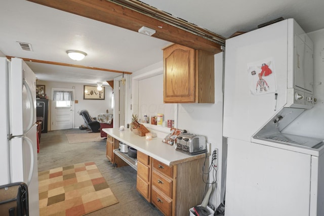 kitchen featuring dark colored carpet, stacked washer and dryer, and white refrigerator