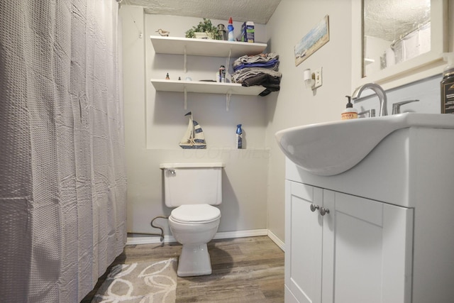 bathroom featuring vanity, a textured ceiling, hardwood / wood-style flooring, and toilet