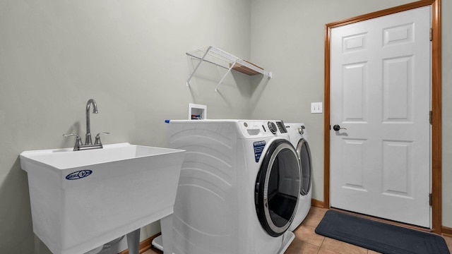 laundry area with light tile patterned floors, washer and clothes dryer, and sink