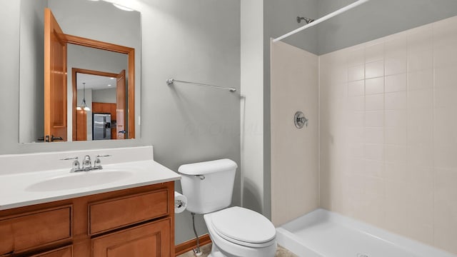 bathroom featuring a tile shower, vanity, and toilet