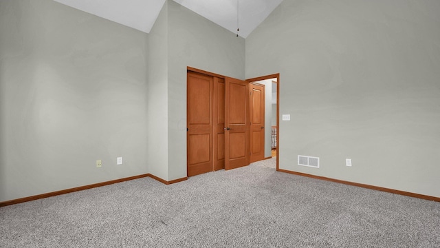 unfurnished bedroom with carpet floors and high vaulted ceiling