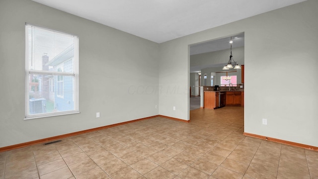 empty room featuring a notable chandelier, light tile patterned flooring, and sink