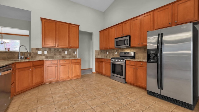 kitchen with light stone countertops, decorative backsplash, stainless steel appliances, an inviting chandelier, and light tile patterned flooring