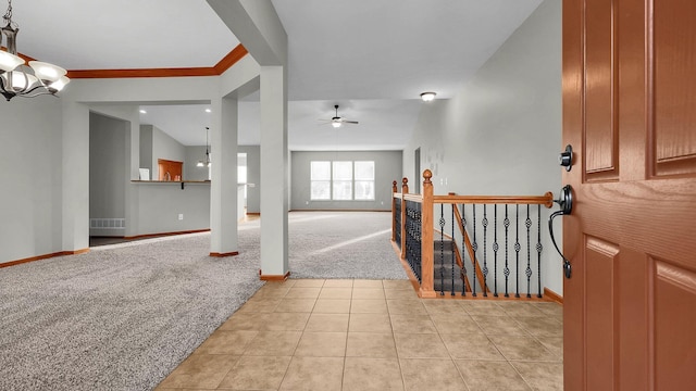 carpeted entryway with ceiling fan with notable chandelier and lofted ceiling