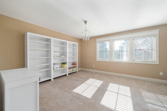 spare room featuring a textured ceiling, a notable chandelier, and light carpet