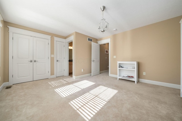 unfurnished bedroom with a notable chandelier and light colored carpet