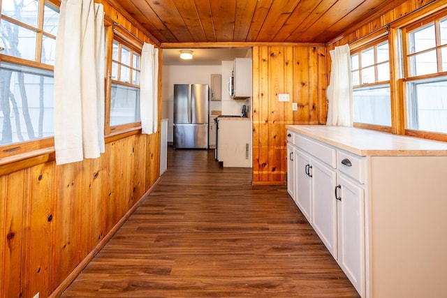 kitchen with white cabinets, dark hardwood / wood-style flooring, stainless steel refrigerator, and plenty of natural light