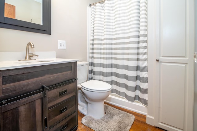 bathroom with hardwood / wood-style floors, vanity, toilet, and walk in shower