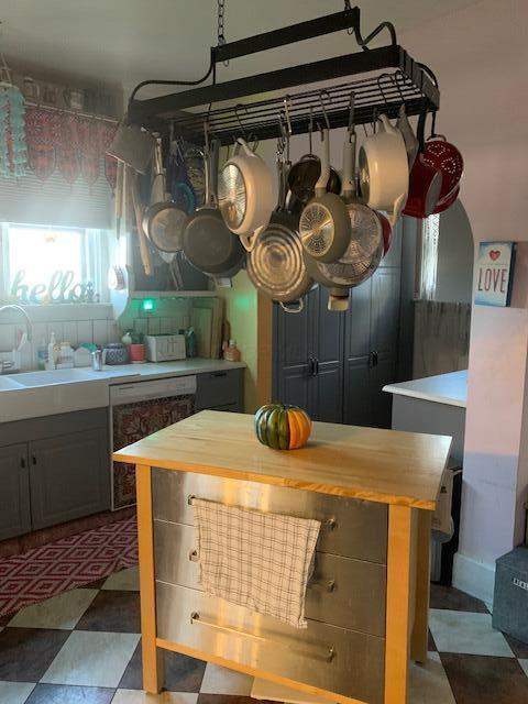 kitchen featuring gray cabinetry, sink, stainless steel dishwasher, a kitchen island, and butcher block counters