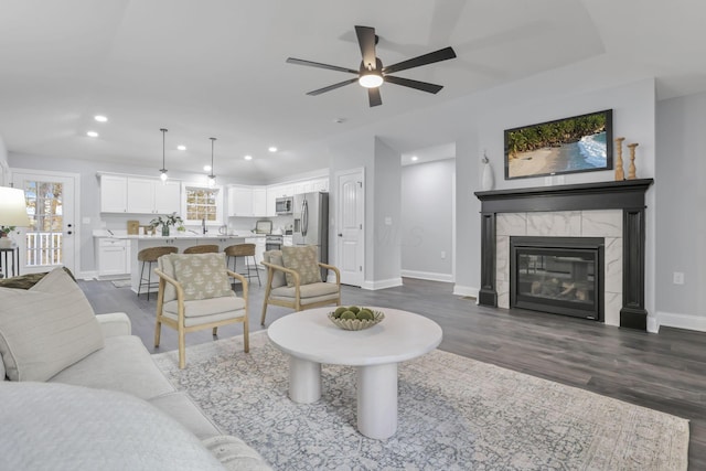 living room featuring ceiling fan, a high end fireplace, and dark hardwood / wood-style floors