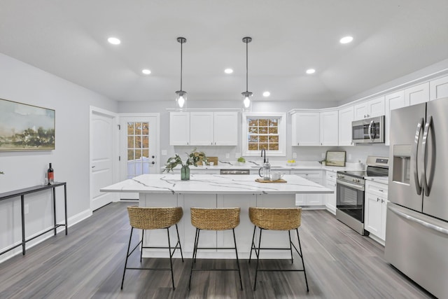 kitchen with pendant lighting, a center island, white cabinetry, and appliances with stainless steel finishes