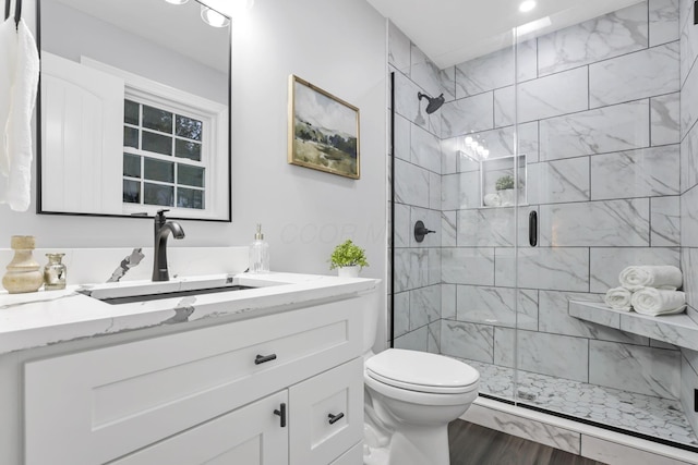 bathroom featuring a shower with door, vanity, wood-type flooring, and toilet