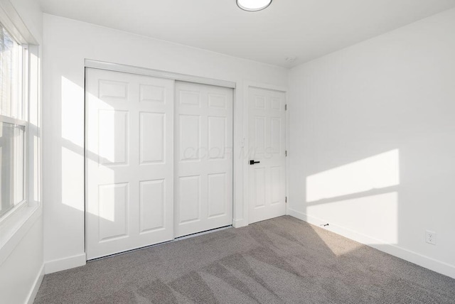 unfurnished bedroom featuring dark carpet and a closet