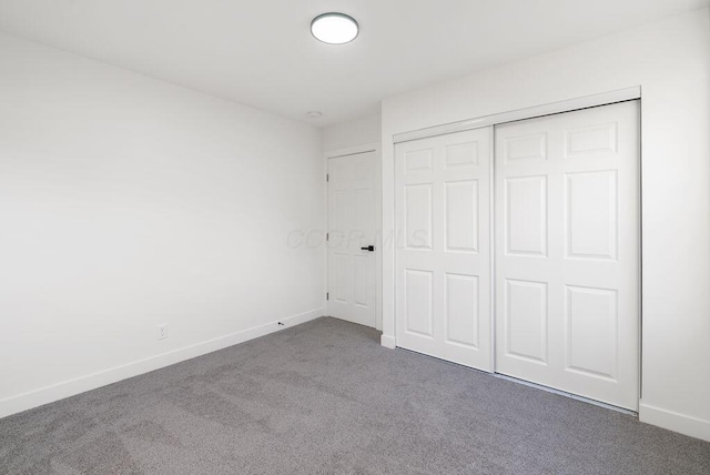 unfurnished bedroom featuring a closet and dark carpet