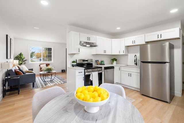 kitchen with white cabinetry, stainless steel appliances, and light hardwood / wood-style flooring