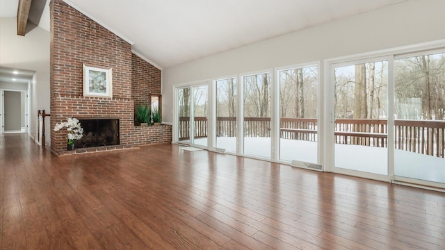 unfurnished living room with high vaulted ceiling, a fireplace, wood finished floors, and beam ceiling