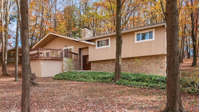 view of front of home featuring stone siding, a chimney, a deck, and brick siding