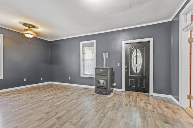 entryway featuring a textured ceiling, ceiling fan, crown molding, light hardwood / wood-style floors, and a wood stove