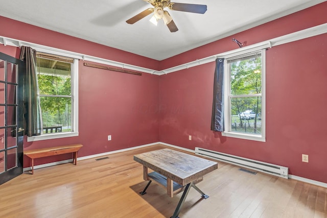 interior space with hardwood / wood-style flooring, ceiling fan, and a baseboard heating unit